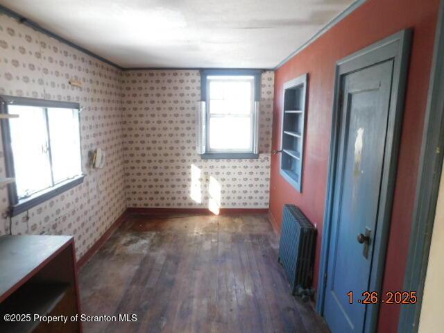 unfurnished room with radiator heating unit and dark hardwood / wood-style flooring