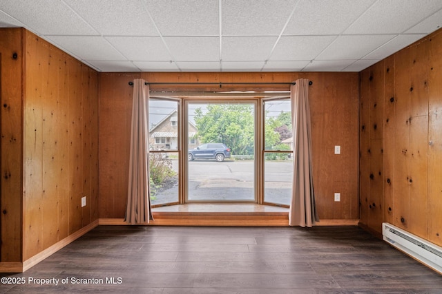 609 Landmesser Ave, West Hazleton, PA 18202 - empty room featuring baseboard heating, wooden walls, wood finished floors, and a drop ceiling