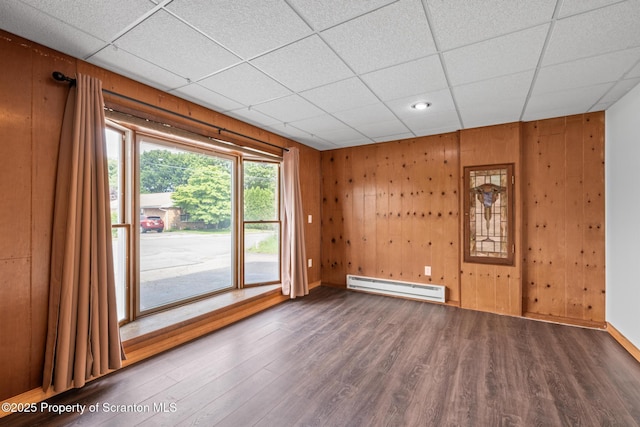 609 Landmesser Ave, West Hazleton, PA 18202 - unfurnished room featuring a baseboard heating unit, wood finished floors, wooden walls, and a drop ceiling