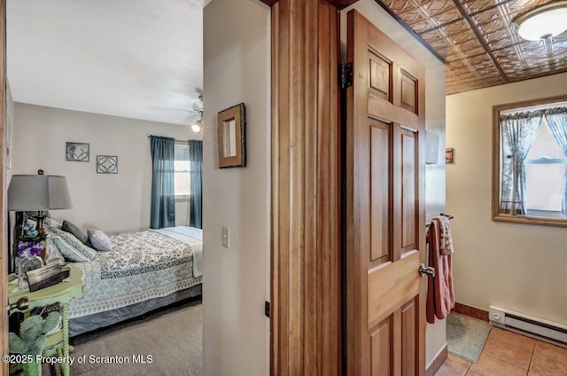 bedroom with a baseboard heating unit and light tile patterned floors