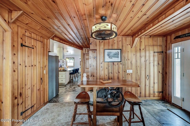 dining space with a wealth of natural light, wood ceiling, and wood walls