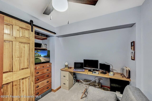 carpeted home office with ceiling fan and a barn door