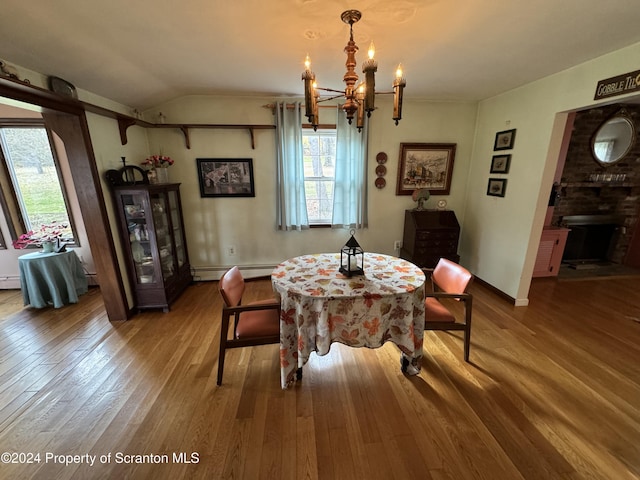 dining space featuring vaulted ceiling, hardwood / wood-style floors, a baseboard heating unit, and an inviting chandelier