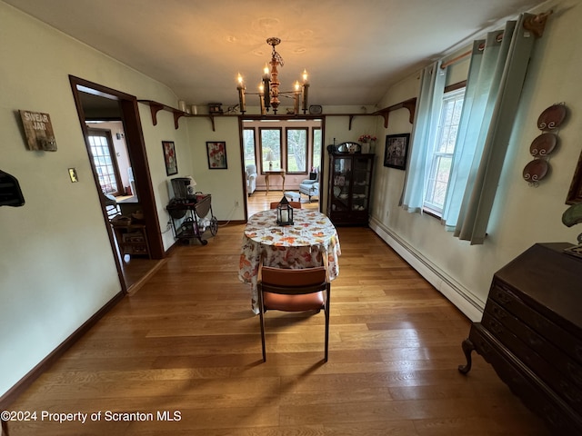 dining area with baseboard heating, hardwood / wood-style floors, and a notable chandelier