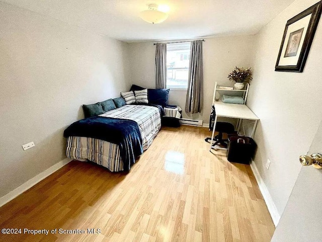 bedroom with hardwood / wood-style flooring and baseboard heating