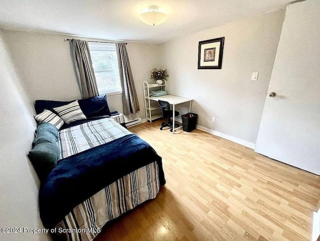 bedroom with hardwood / wood-style flooring and a baseboard heating unit