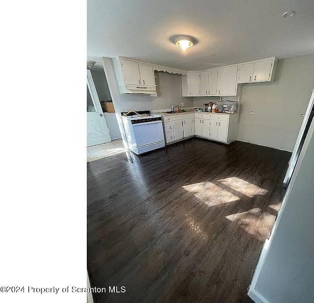 kitchen featuring white range, dark hardwood / wood-style floors, white cabinetry, and sink