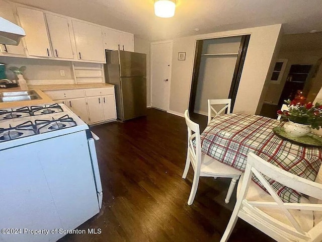 kitchen with exhaust hood, white cabinets, sink, stainless steel fridge, and white range with gas cooktop