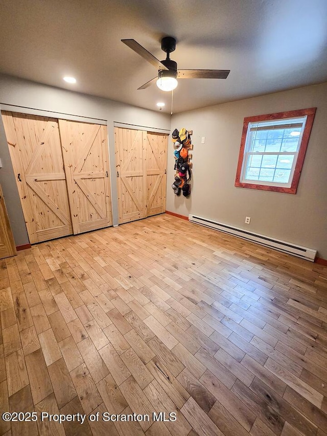 unfurnished bedroom with ceiling fan, baseboard heating, and light hardwood / wood-style floors