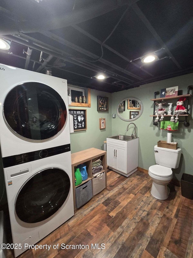 washroom featuring stacked washer and dryer, dark hardwood / wood-style flooring, and sink