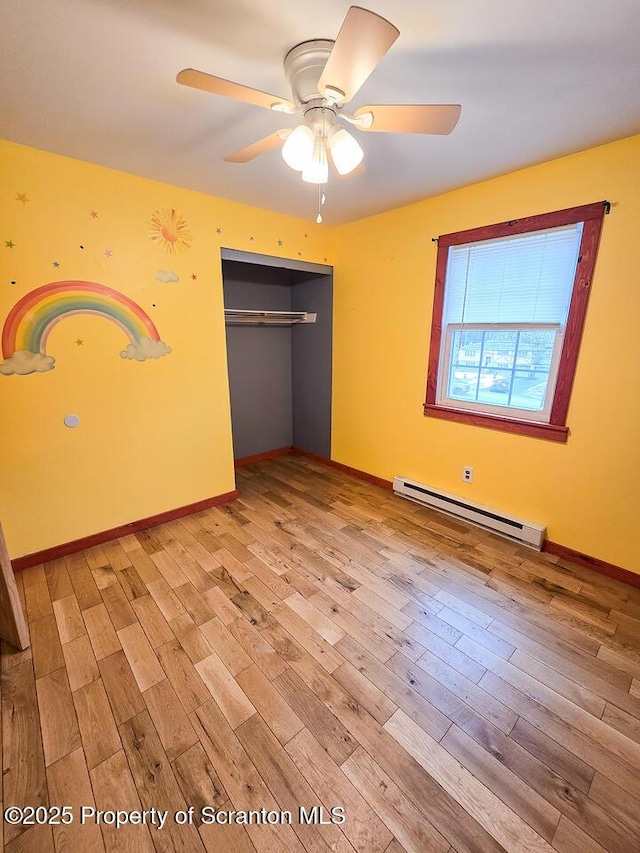 unfurnished bedroom featuring a baseboard radiator, a closet, ceiling fan, and light wood-type flooring