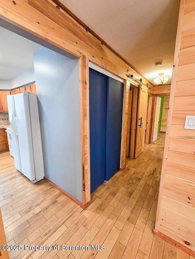 hall with a barn door and light hardwood / wood-style floors