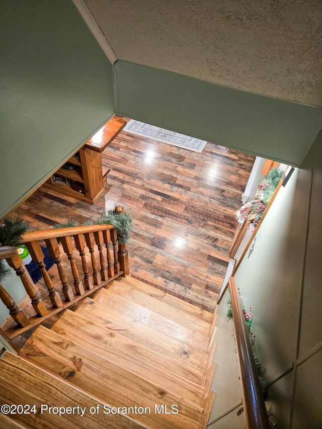 stairway featuring wood-type flooring and a textured ceiling