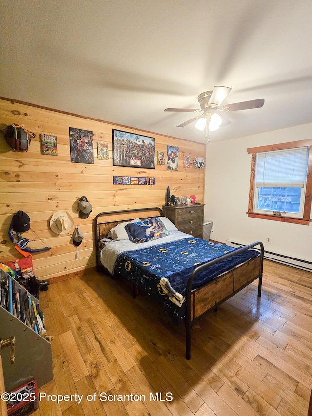 bedroom featuring hardwood / wood-style flooring, ceiling fan, and wood walls