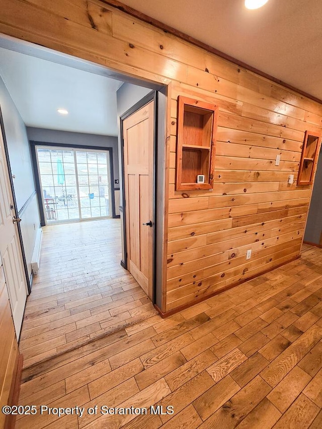 hallway featuring light hardwood / wood-style flooring and wood walls