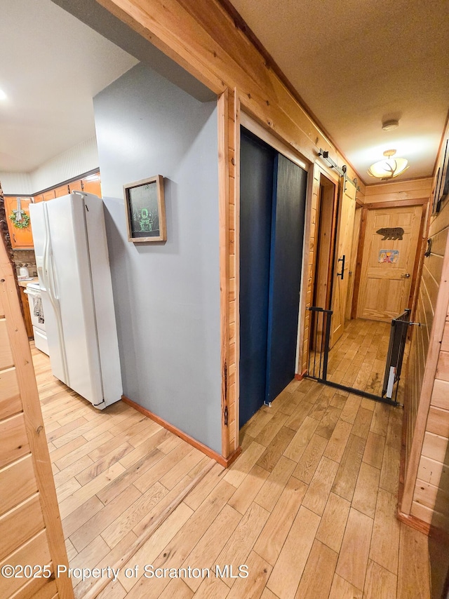 hallway with a barn door and light hardwood / wood-style floors