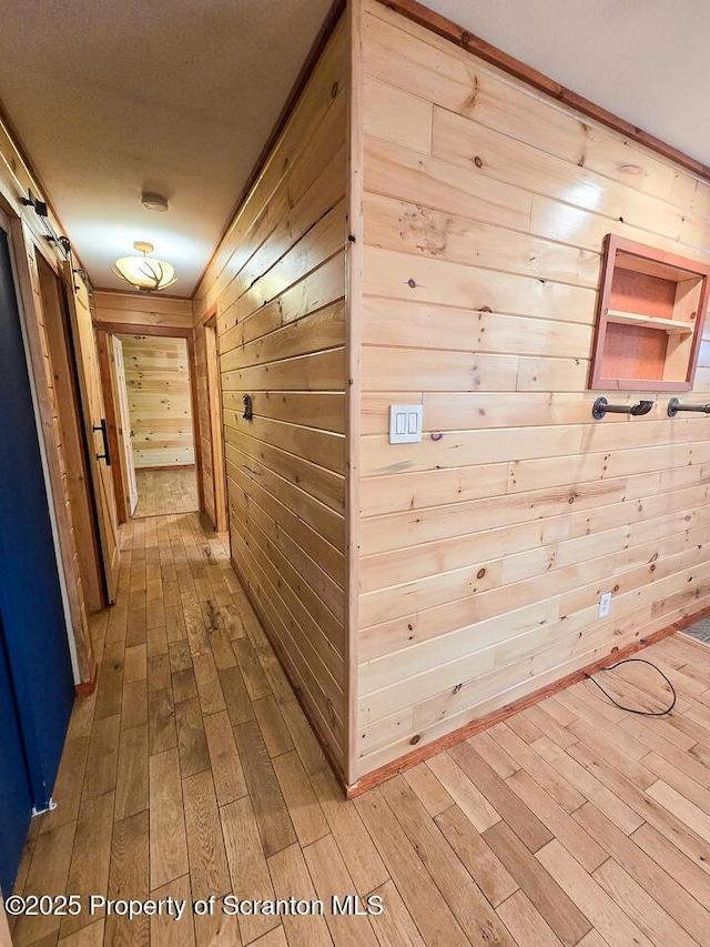 hall with hardwood / wood-style floors, a barn door, and wood walls