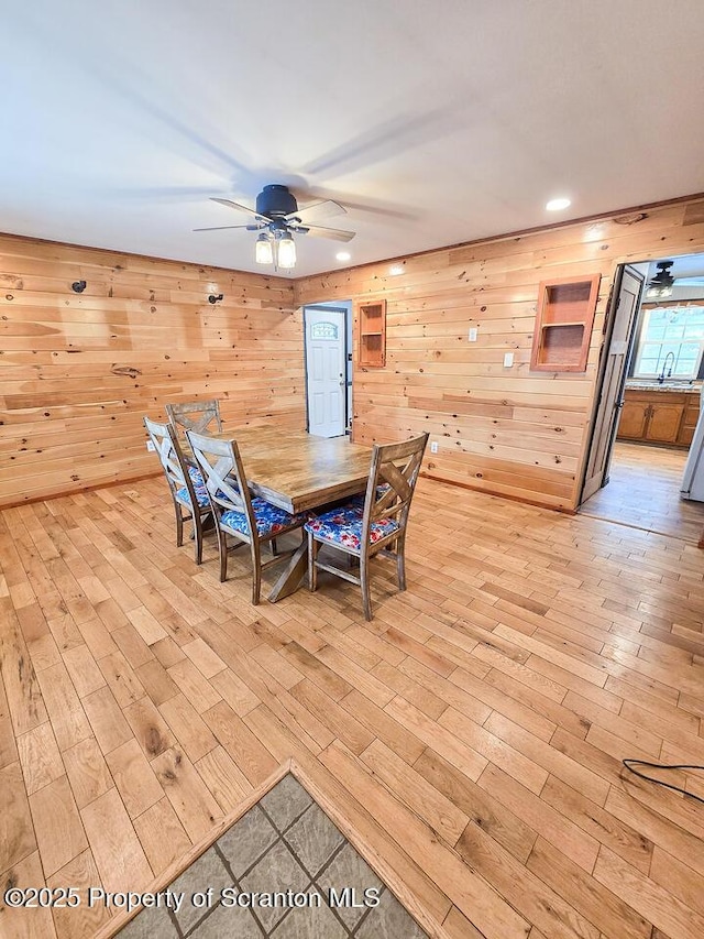 dining space featuring wooden walls, light hardwood / wood-style floors, and ceiling fan