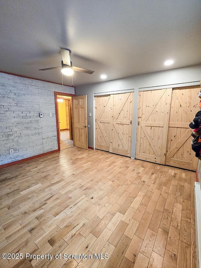 empty room featuring ceiling fan, a barn door, and light hardwood / wood-style floors