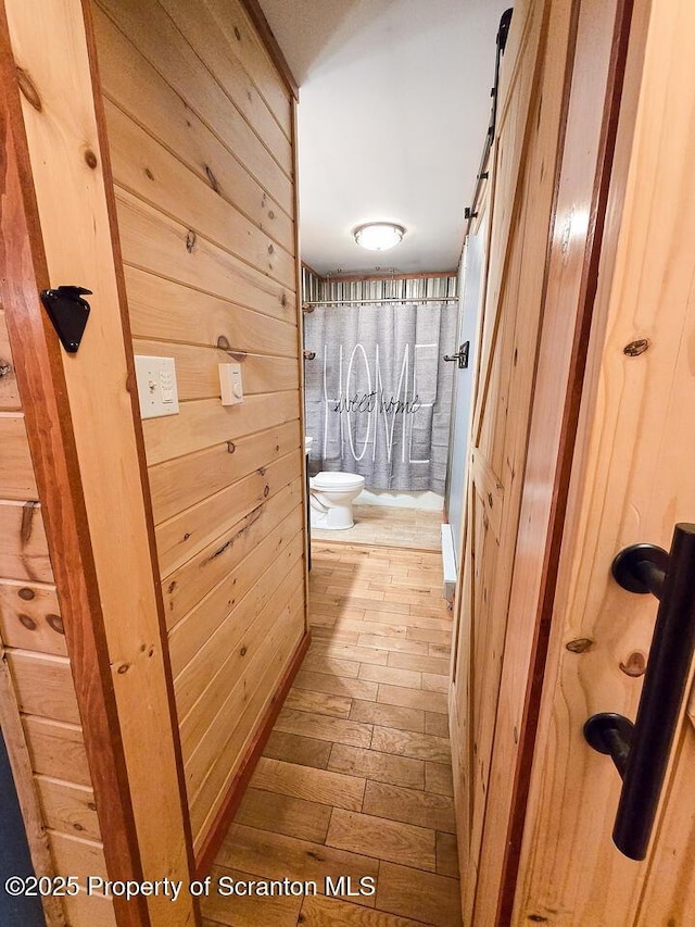 bathroom featuring hardwood / wood-style flooring, wooden walls, and toilet