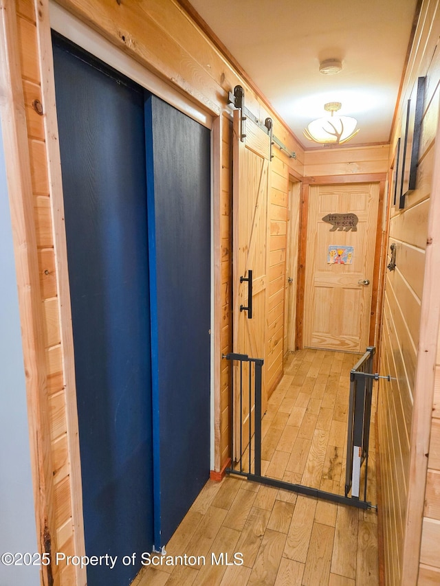 corridor featuring hardwood / wood-style flooring, a barn door, and wood walls