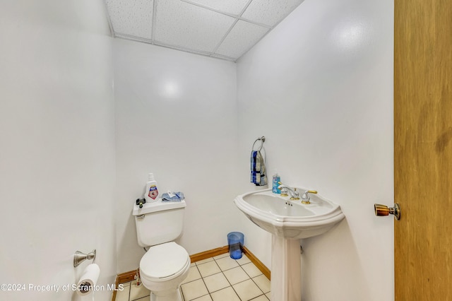 bathroom with tile patterned flooring, a paneled ceiling, toilet, and sink