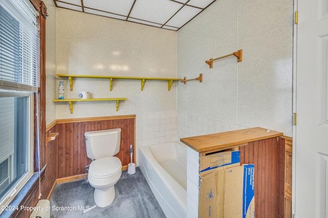 bathroom featuring wooden walls, toilet, and a bathing tub