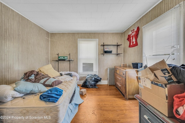 bedroom with radiator heating unit, ornamental molding, and light hardwood / wood-style flooring