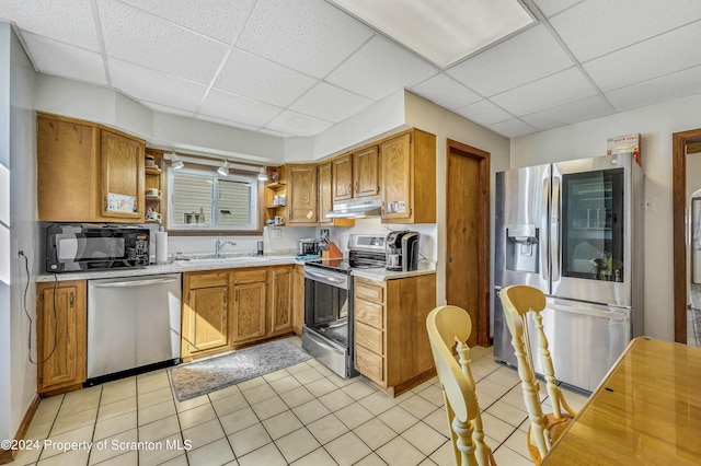 kitchen featuring a paneled ceiling, sink, light tile patterned flooring, and stainless steel appliances