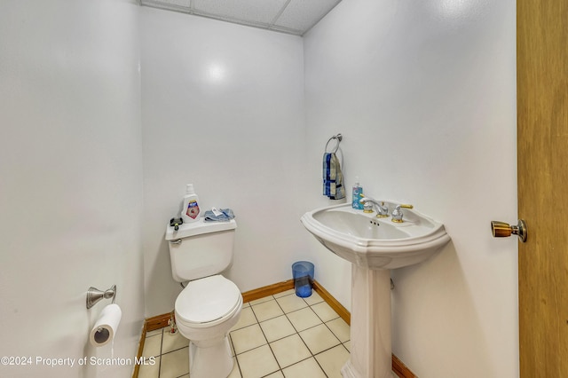 bathroom featuring tile patterned flooring, a drop ceiling, toilet, and sink