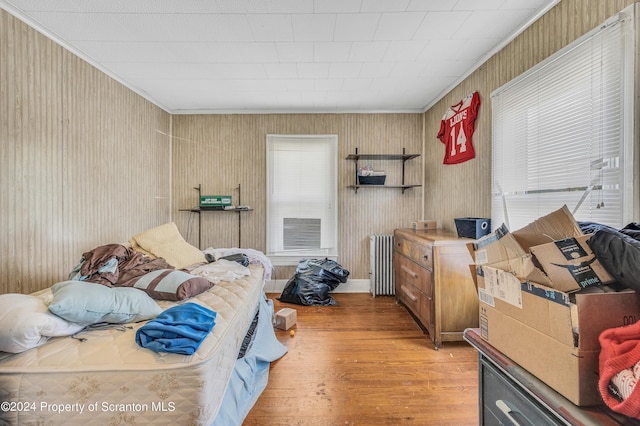 bedroom with wood-type flooring, radiator heating unit, and crown molding