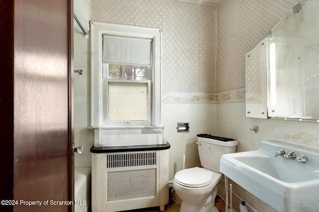 bathroom with sink, tile walls, radiator heating unit, toilet, and a tub