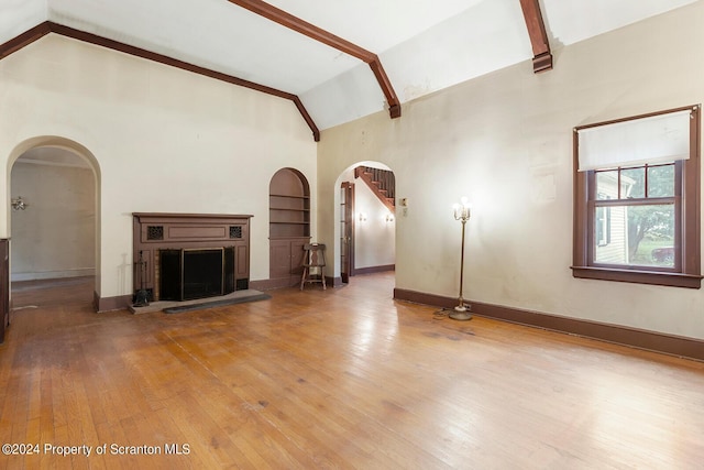 unfurnished living room featuring built in shelves, lofted ceiling, and wood-type flooring