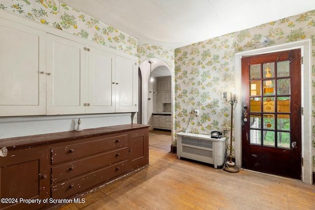 interior space with white cabinets, light hardwood / wood-style floors, and heating unit