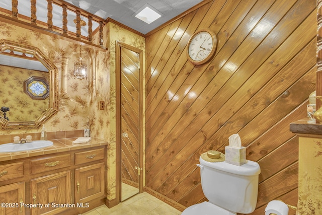 bathroom featuring wooden walls, ornamental molding, toilet, tile patterned floors, and vanity