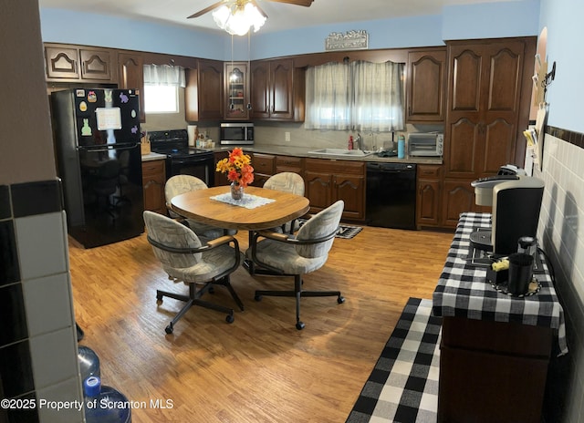 kitchen with light wood-style flooring, a sink, dark brown cabinetry, a ceiling fan, and black appliances