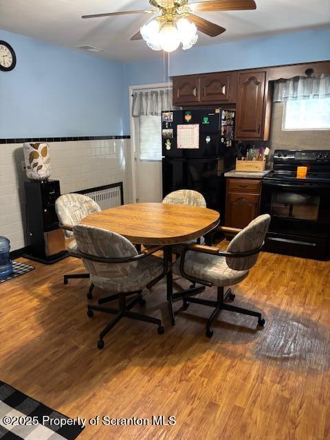 dining room featuring wainscoting, light wood-style flooring, and ceiling fan