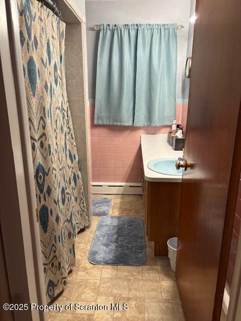 bathroom with a baseboard radiator, vanity, tile walls, a shower with curtain, and tile patterned flooring