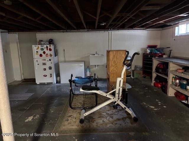 below grade area featuring freestanding refrigerator and a sink