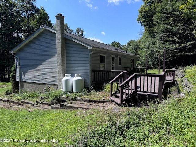 rear view of house featuring a deck and a lawn