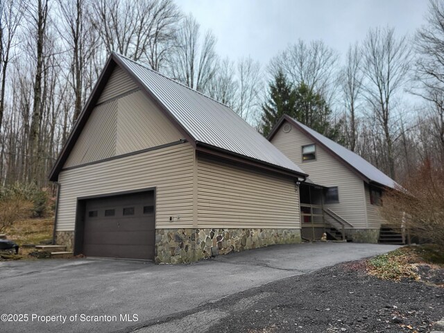 1445 Heart Lake Rd, Scott Twp, PA 18433 - view of side of home featuring a metal roof, asphalt driveway, a garage, stone siding, and entry steps
