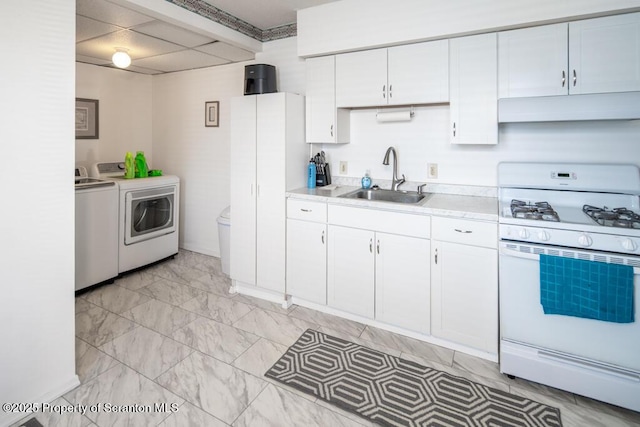 kitchen featuring white range with gas stovetop, washer and dryer, a sink, under cabinet range hood, and light countertops