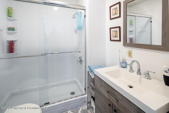 full bath with a stall shower, toilet, and vanity