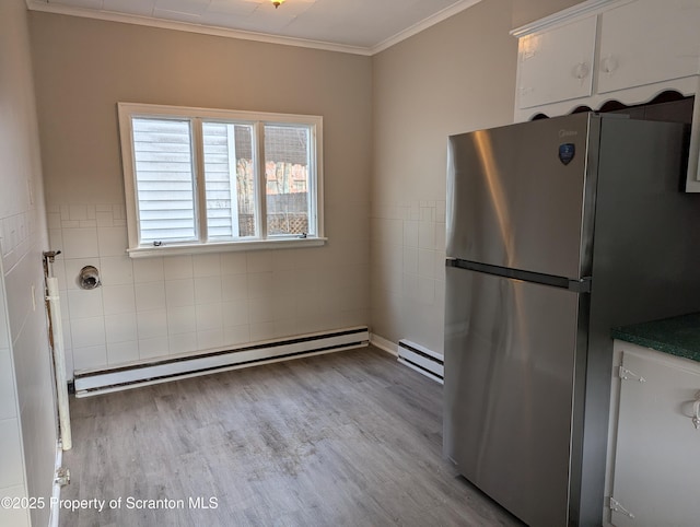 kitchen with light wood-type flooring, stainless steel refrigerator, a baseboard heating unit, and crown molding