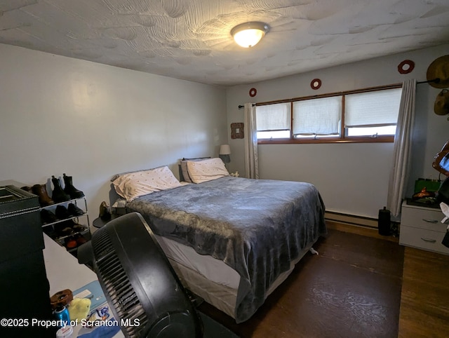 bedroom featuring baseboard heating and dark wood-type flooring