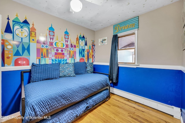 bedroom with a baseboard radiator and hardwood / wood-style flooring