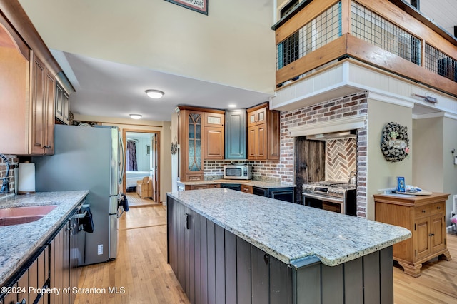 kitchen with a center island, light stone counters, light wood-type flooring, and stainless steel appliances