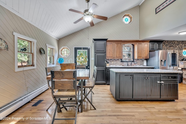 kitchen with stainless steel fridge with ice dispenser, light stone counters, a center island, and light hardwood / wood-style floors