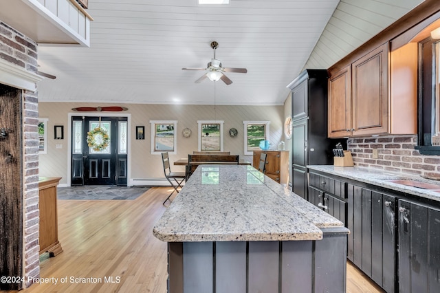 kitchen with a kitchen island, light stone countertops, light hardwood / wood-style flooring, and a baseboard radiator