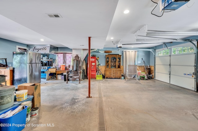 garage with stainless steel fridge and a garage door opener